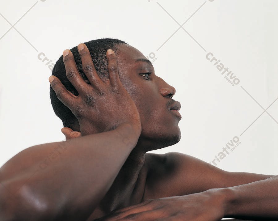 Homem negro com as mãos no cabelo perfil