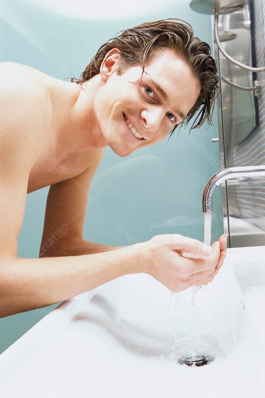 Homem lavando as mãos sorrindo no banheiro