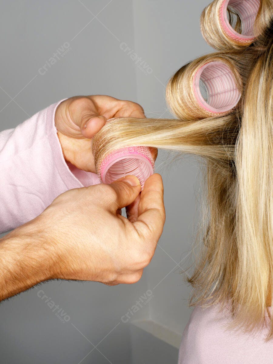 Cabelo loiro sendo enrolado em bobes rosa