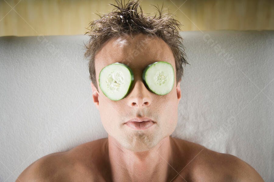 Homem com fatias de pepino nos olhos