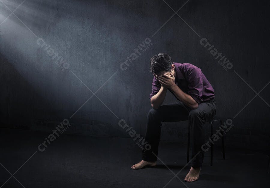 Homem triste sentado em ambiente escuro