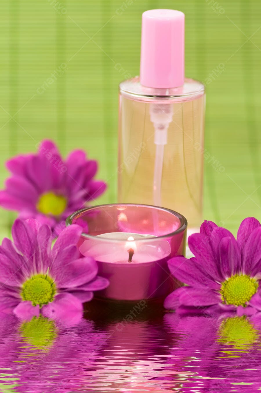 Vela rosa e perfume com flores roxas