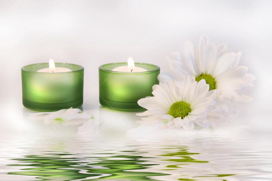 Velas verdes e margaridas brancas em reflexo d'água