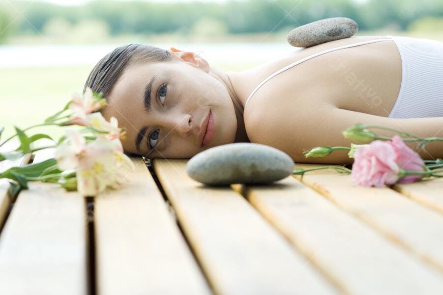 Mulher relaxando com pedras quentes e flores