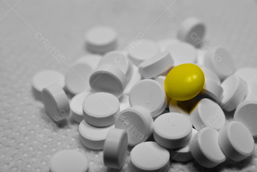 Comprimido amarelo entre comprimidos brancos