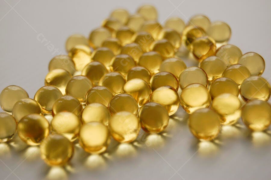 Cápsulas de óleo dourado sobre fundo claro