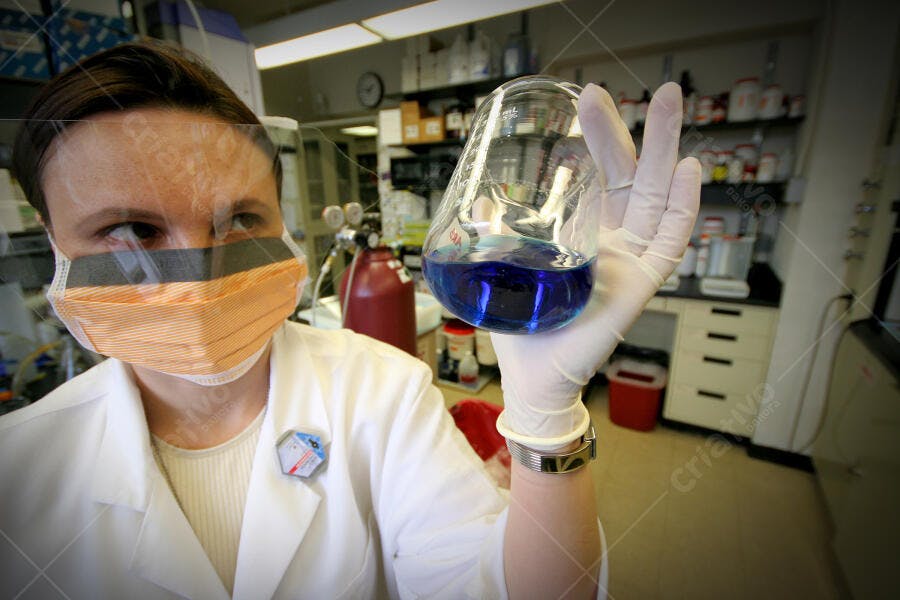 Cientista segurando béquer azul em laboratório