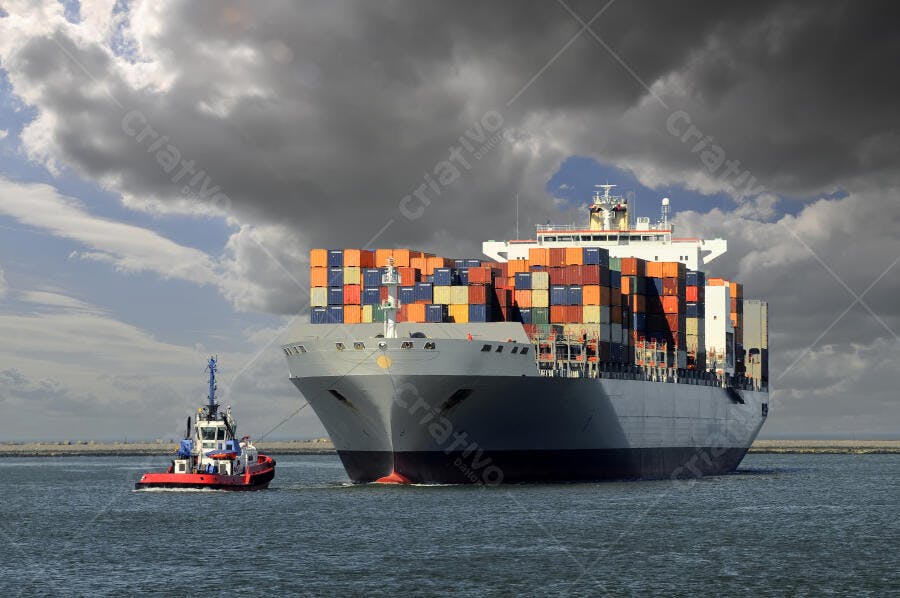 Navio cargueiro sendo rebocado em dia nublado