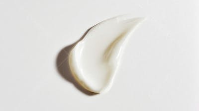 Macro de alta resolução de uma textura de creme sobre fundo branco, transmitindo limpeza e sofisticação 