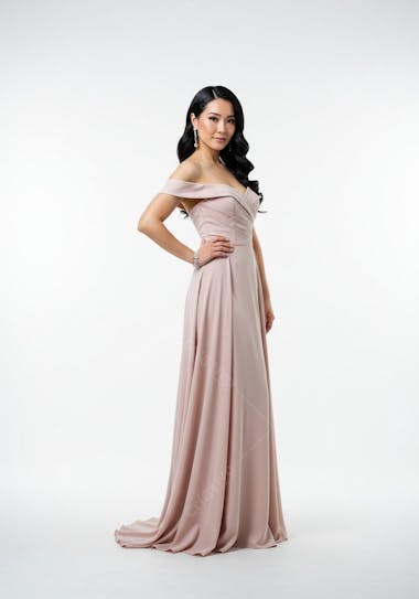 An Asian woman in a stylish light pink, pastel-toned maxi dress against a clean white background. The dress features an off-shoulder design and flows gracefully. The model projects confidence.