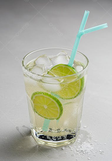 Refreshing cocktail in a glass with lime slices, ice and a light green straw. Light and vibrant tones, light gray background. Light and fresh atmosphere.