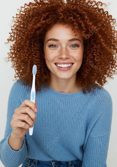 Mulher ruiva sorrindo com escova de dente