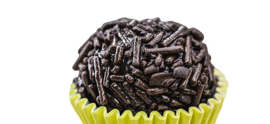 Brigadeiro de chocolate escuro com granulado em forminha amarela fundo branco