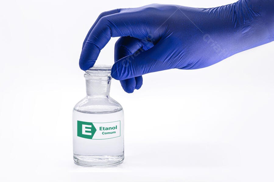 Mão com luva azul segurando frasco de etanol comum em laboratório