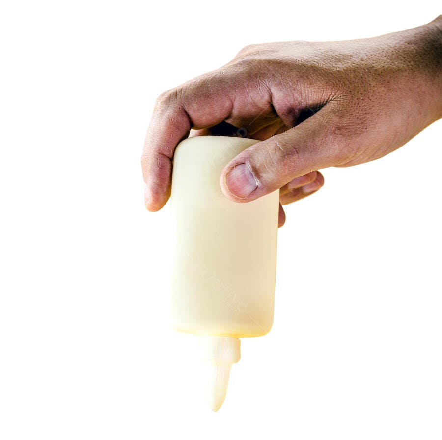 Mão segurando garrafa de cola branca inclinada para uso em fundo branco isolado