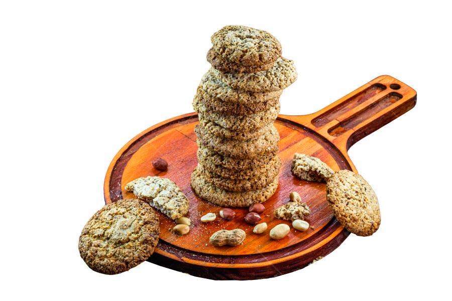 Biscoitos integrais empilhados com amendoim na tábua de madeira rústica e fundo branco