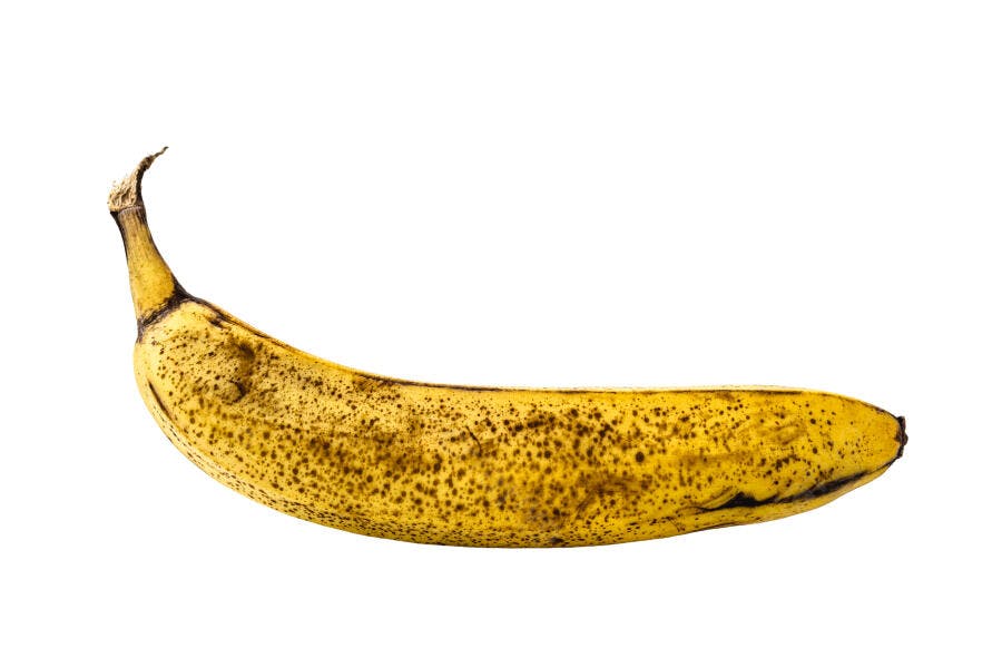 Banana madura amarela com pintas marrons isolada em fundo branco