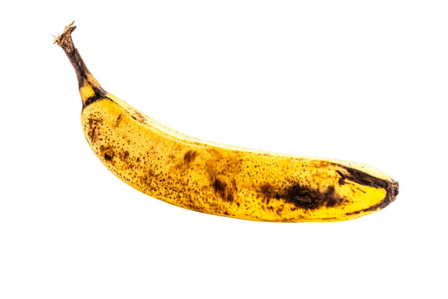 Banana amarela madura com manchas escuras em fundo branco