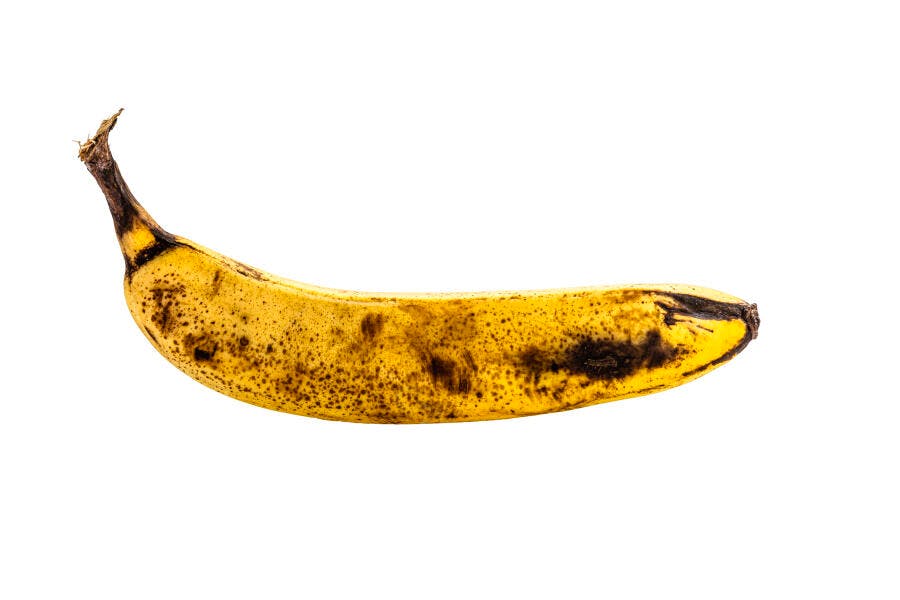 Banana madura amarela com pintas marrons isolada em fundo branco