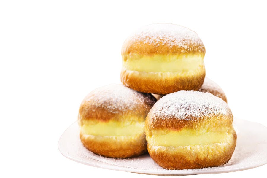 Sonhos recheados com creme e açúcar de confeiteiro em prato branco