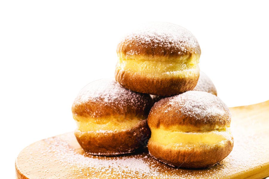 Sonhos recheados com creme e açúcar de confeiteiro em tábua de madeira clara