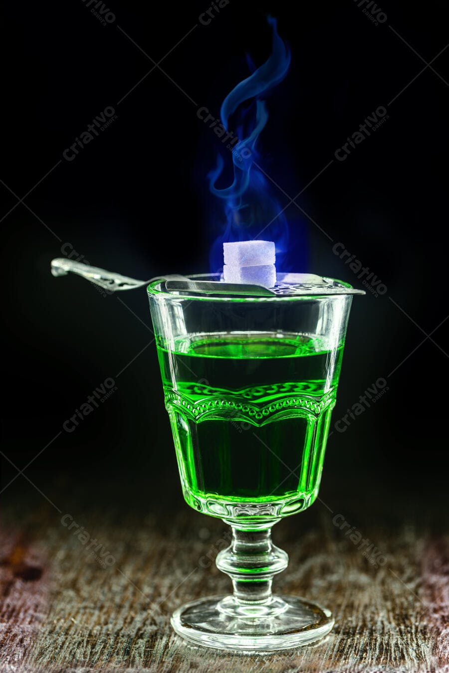 Absinto verde em copo com ritual de açúcar flamejante e fumaça azul