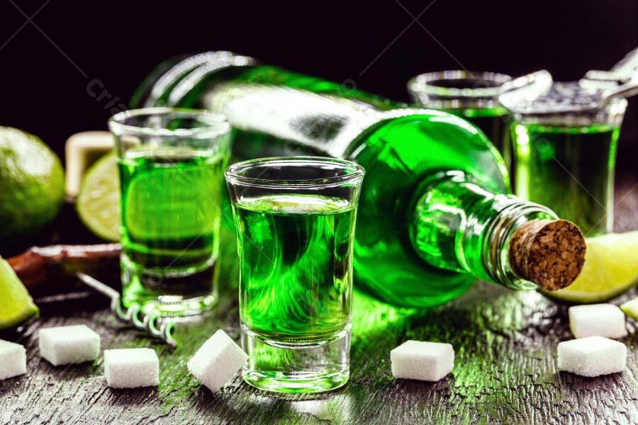 Bebida absinto verde em garrafa e copos shot com limão e açúcar