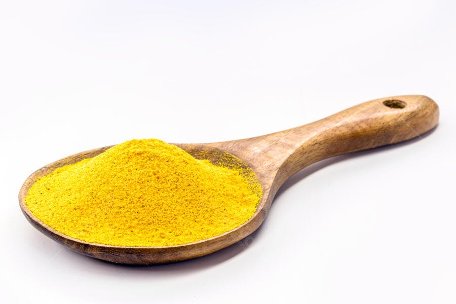 Cúrcuma em pó amarelo vibrante em colher de madeira