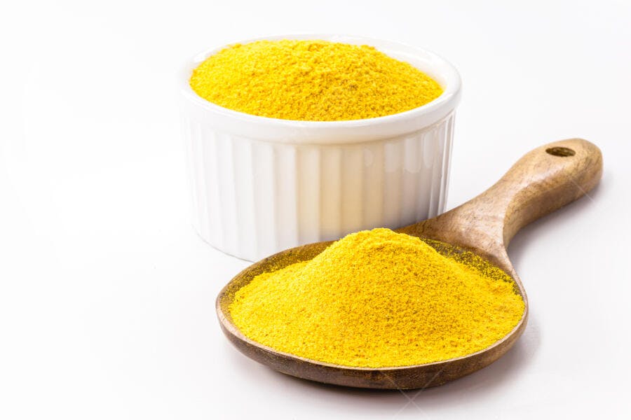 Cúrcuma em pó amarela em tigela branca e colher de madeira