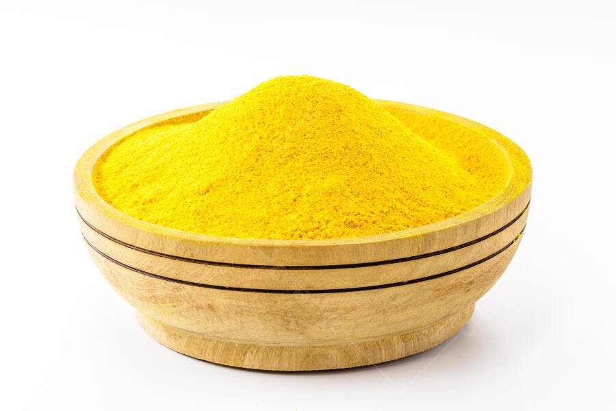 Cúrcuma em pó amarelo vibrante em tigela de madeira com fundo branco