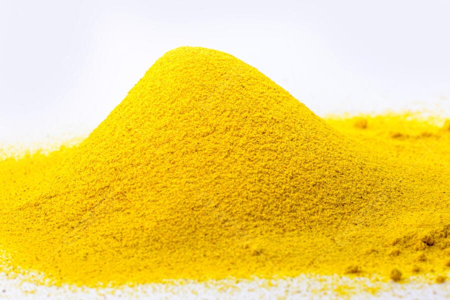 Pó de cúrcuma amarelo vibrante em pilha sobre fundo branco