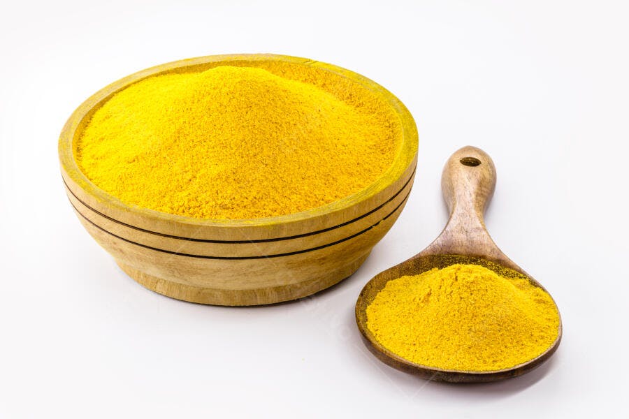 Tigela e colher de pau com açafrão da terra em pó amarelo vibrante