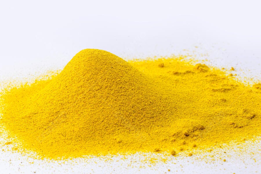 Pó amarelo brilhante de cúrcuma sobre fundo branco minimalista
