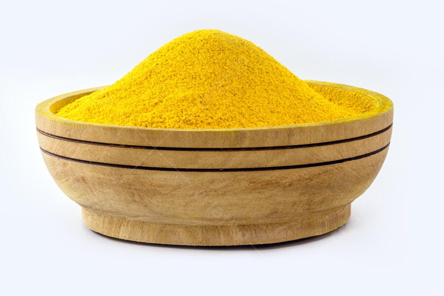 Pó de cúrcuma vibrante em tigela de madeira natural fundo branco