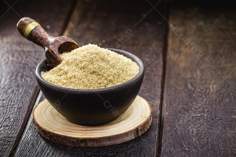 Açúcar mascavo em tigela preta com colher de pau em mesa rústica