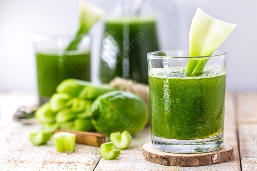 Suco verde detox fresco com aipo e limão em tábua de madeira