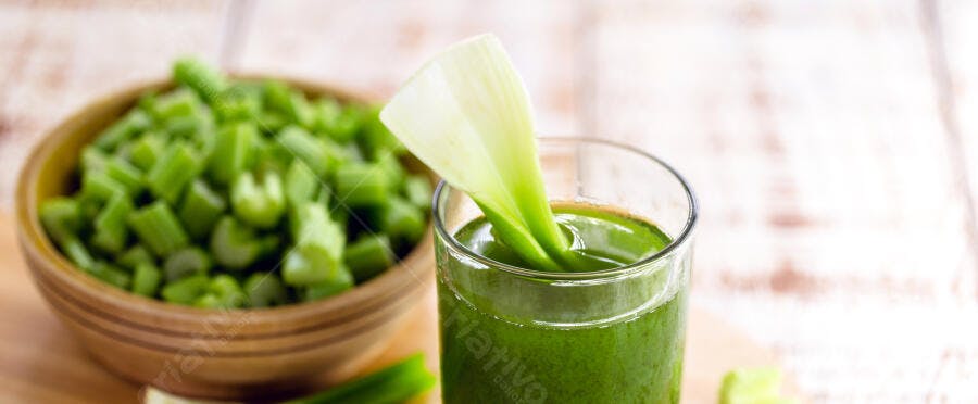 Suco de aipo verde fresco com talo em copo e aipo picado