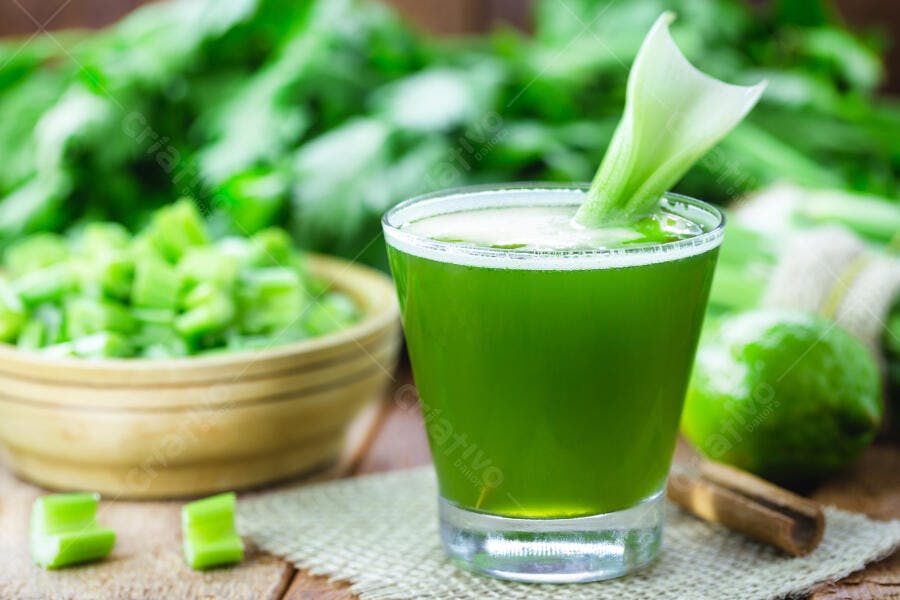 Suco verde fresco com aipo em copo e ingredientes saudáveis na mesa de madeira