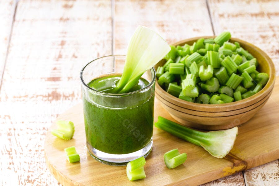 Suco de aipo verde fresco em copo com talos de aipo na mesa de madeira rústica