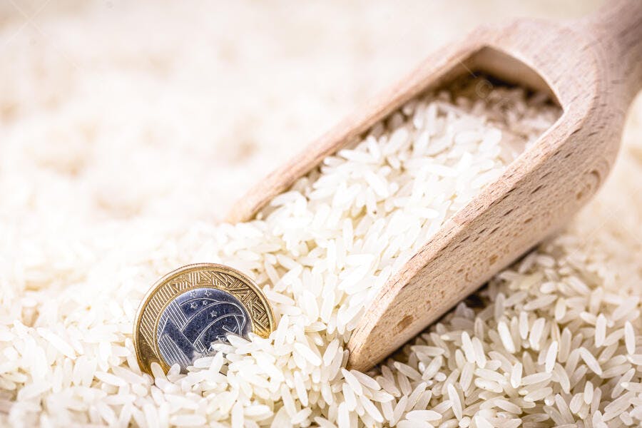 Arroz branco com moeda de real e pá de madeira custo de vida