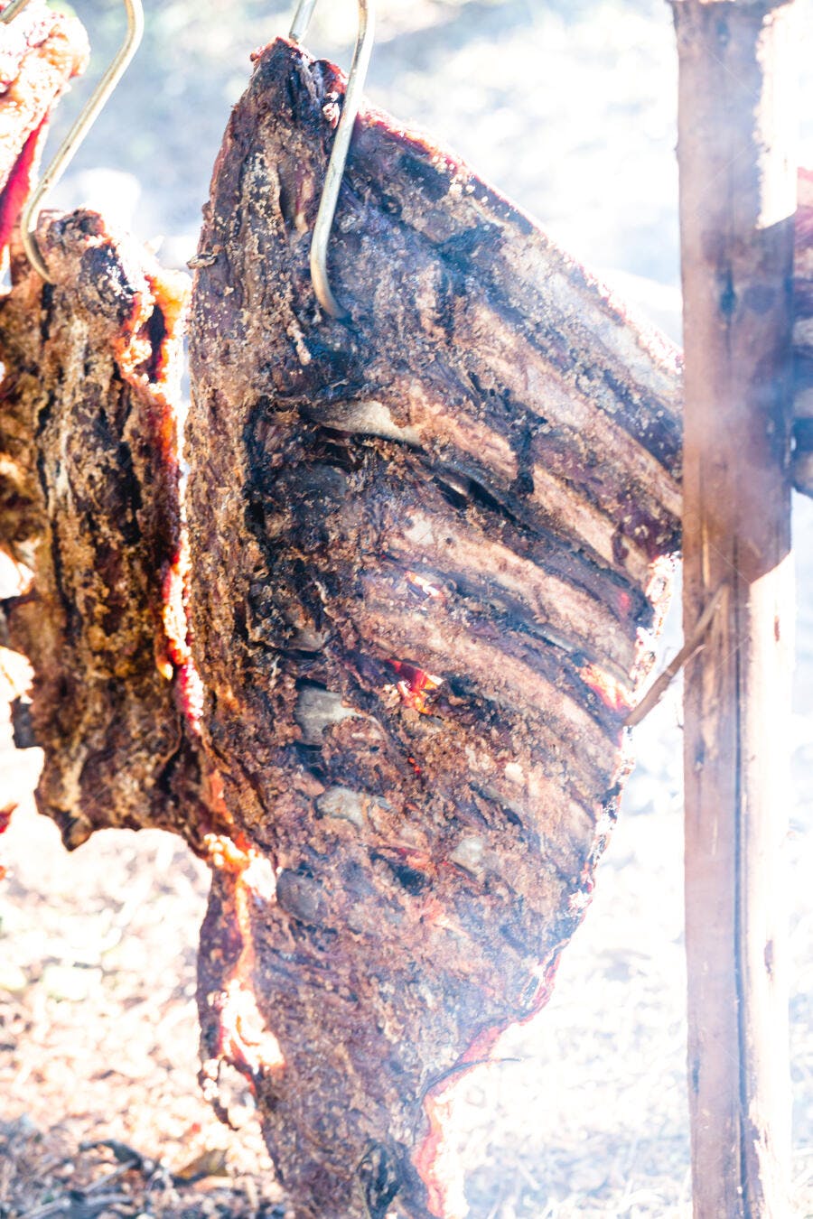 Costelão de boi assado no fogo de chão estilo gaúcho com fumaça