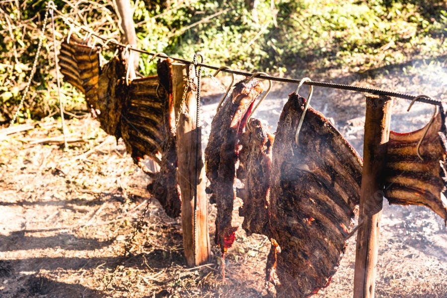 Costelão de carne assando ao ar livre em churrasco fogo de chão rústico