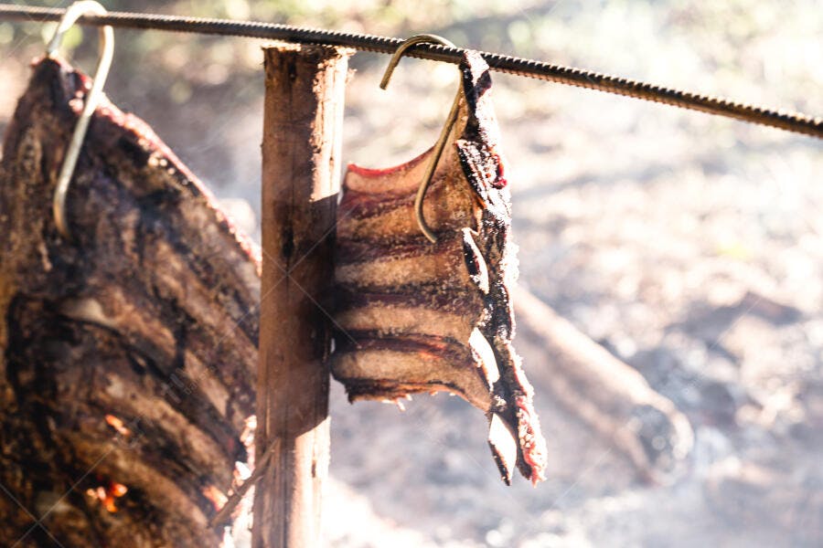 Costelão bovino assando no fogo de chão churrasco gaúcho tradicional