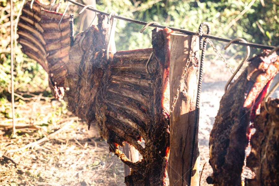 Churrasco de costela assando em fogo de chão ao ar livre
