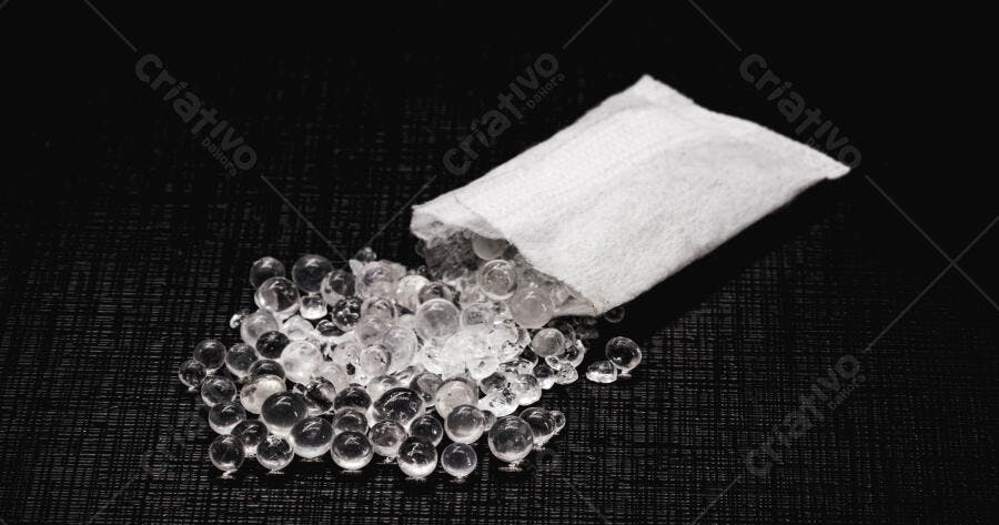 Sílica gel transparente e sachê de dessecante branco em fundo escuro