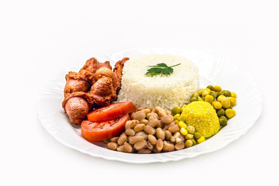 Prato de comida brasileira com arroz branco, feijão, linguiça frita, farofa e legumes fresco