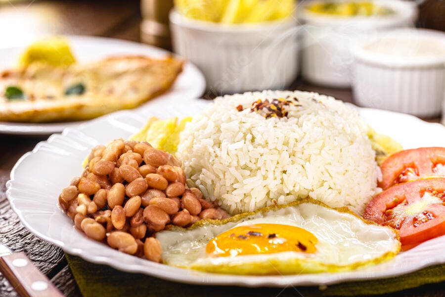 Prato de arroz branco, feijão, ovo frito e tomate fresco
