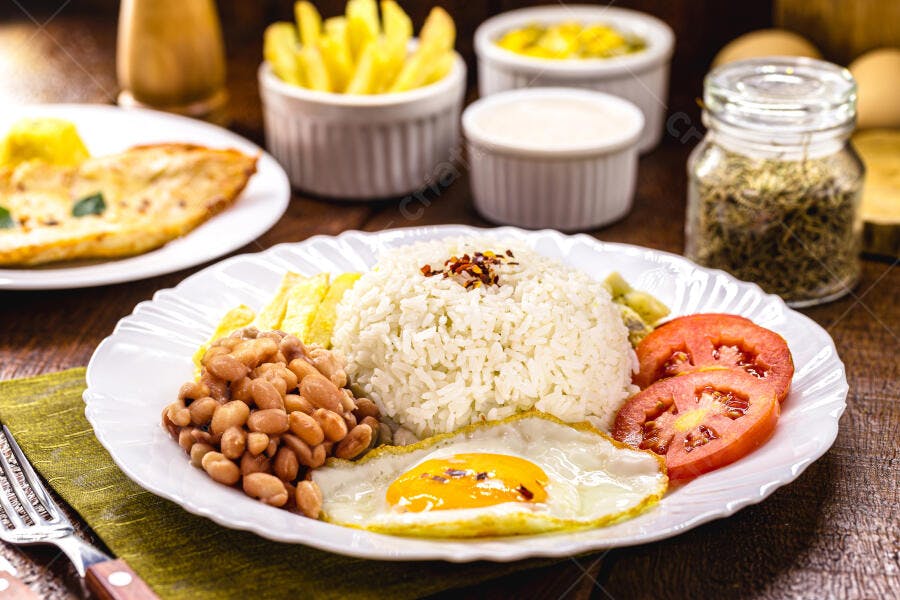 Prato de comida brasileira com arroz feijão ovo frito e batatas no almoço caseiro