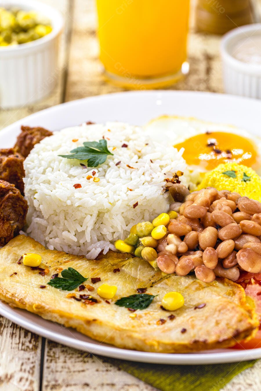 Prato colorido de arroz feijão ovos fritos e peito de frango grelhado com suco