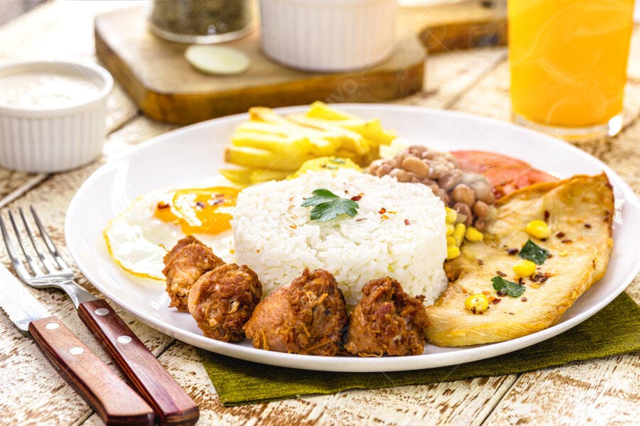 Prato de comida caseira brasileira com arroz ovo feijão e carne frita em mesa rústica